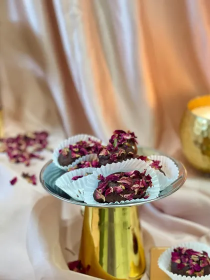 My Shahi Khajoor are a royal treat. I take premium Afghani dates, center them with a roasted almond, coat them in silky chocolate, and hand-roll them in a bed of fragrant rose petals.