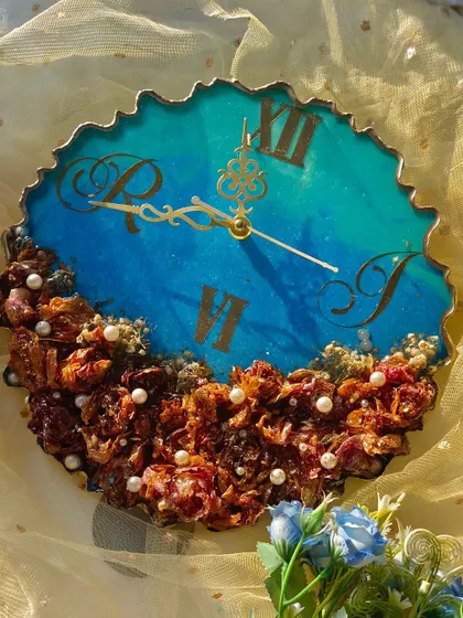 This geode-style clock features a beautiful blue and floral design. The preserved flowers are arranged at the bottom, and the top has a lovely ocean-inspired resin pour.