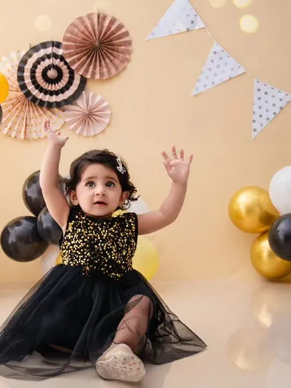 This little girl is reaching for the stars in her sparkly black dress, part of a fun and dynamic travel-themed setup.