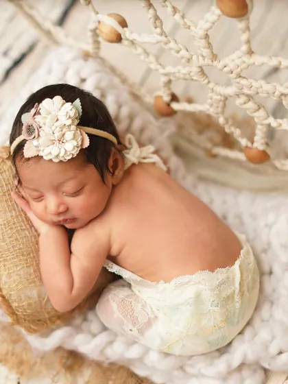 A sweet side profile of the newborn in her boho-chic setup, highlighting her delicate features and lace outfit.