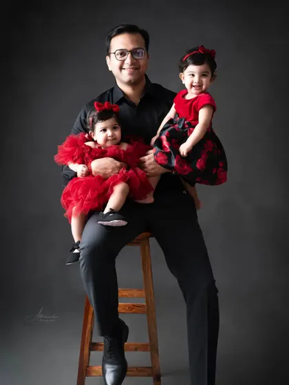 A proud father with his two beautiful twin daughters, all dressed in matching red and black.