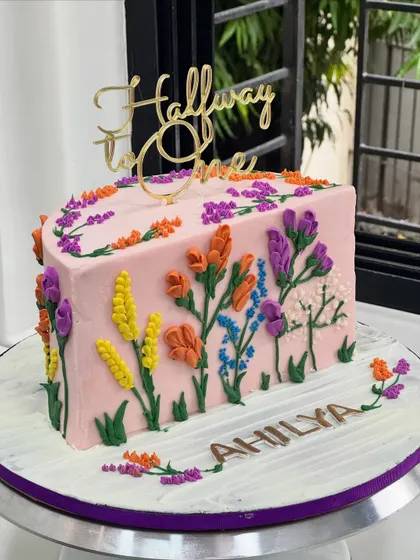 Halfway to One and already blooming with colors! This unique half-cake is decorated with a garden of hand-piped buttercream flowers to celebrate a six-month milestone.