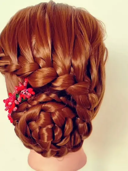 A beautifully woven bun hairstyle accented with small, bright red flowers. This style adds a pop of color and is a great option for festive occasions or to match a colorful outfit.