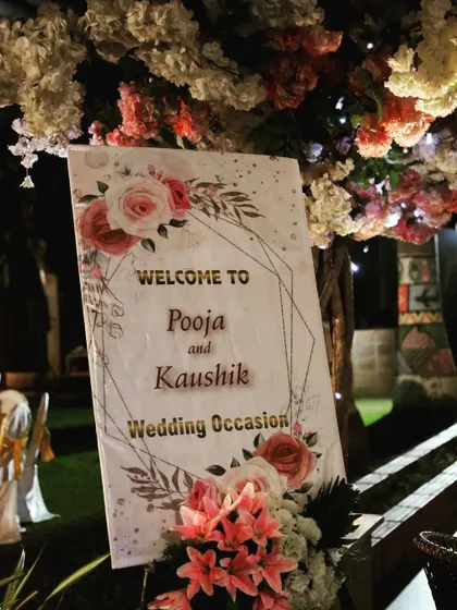 This close-up shows the welcome sign nestled under a tree decorated with flowers. Integrating signage with the venue's natural elements is a detail I focus on.