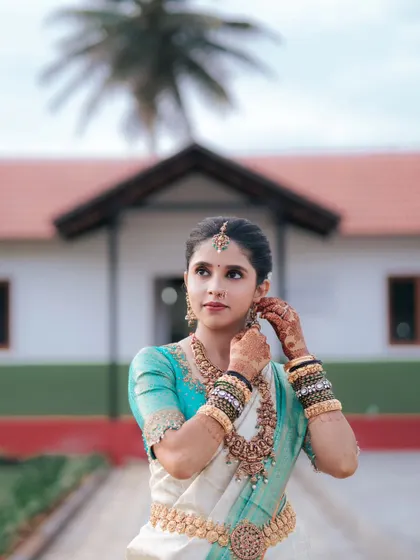 A beautiful candid shot of the bride adjusting her earring, a quiet moment of preparation before the main ceremony.