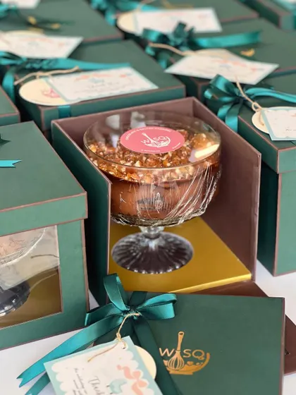 A close-up of our emerald green gift box, showing the dessert trifle nestled inside. The custom sticker and ribbon add a final touch of class.