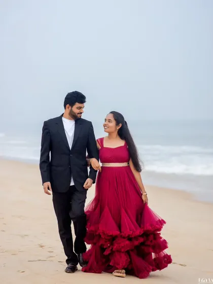 A candid moment of a couple walking arm-in-arm along the shore, sharing a smile. This captures the easy, natural romance of a pre-wedding beach walk.