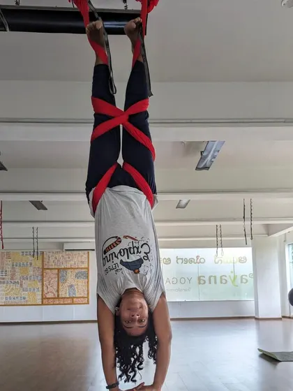 An inverted student smiles for the camera during a weekend aerial session. The studio is always buzzing with energy.