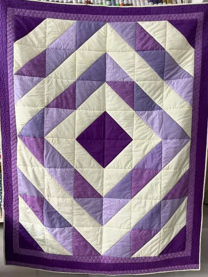 A "Diamond in a Square" quilt in various shades of purple. The simple geometric design is clean and modern.