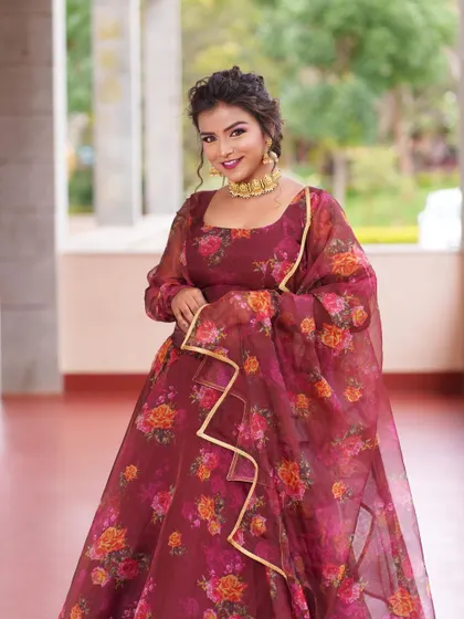 A three-quarter view of the model smiling, looking radiant in the floral organza lehenga.