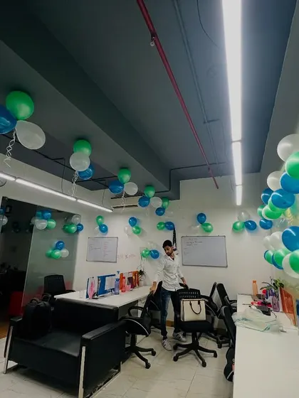 The entire office space is filled with balloon clusters hanging from the ceiling, creating a fun and celebratory atmosphere for a team event.