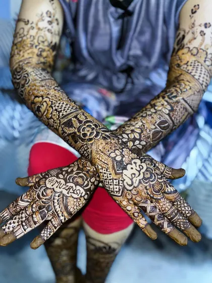 This Nikah bride's henna includes her name, "Muzna," and her groom's name, "Muzassir," on each hand.