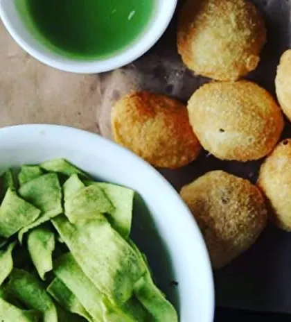 A healthy snacking platter featuring roasted palak (spinach) chips and baked puris, perfect for dipping.