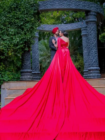 An epic shot from behind, showing the full, magnificent spread of the red gown's train on the steps. This angle emphasizes the grandeur and fairy-tale quality of the moment.