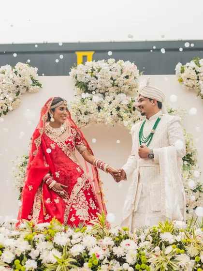 Holding hands, surrounded by a sea of flowers. This shot of Rahul and Riya shows the beautiful connection between the couple during their wedding ceremony, framed by the elegant decor.