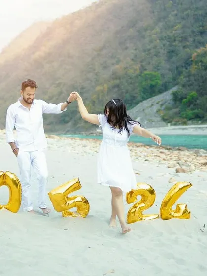 A playful and happy moment captured on a beach, as a couple dances in front of their save-the-date balloons.