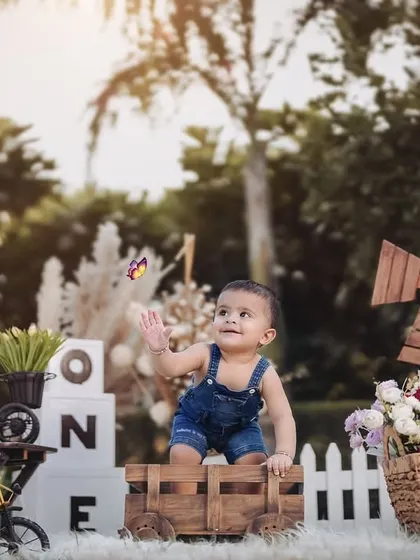 A beautiful, wide shot of a rustic farm-themed outdoor setup. This little boy is captivated by a butterfly, creating a magical and candid photograph.