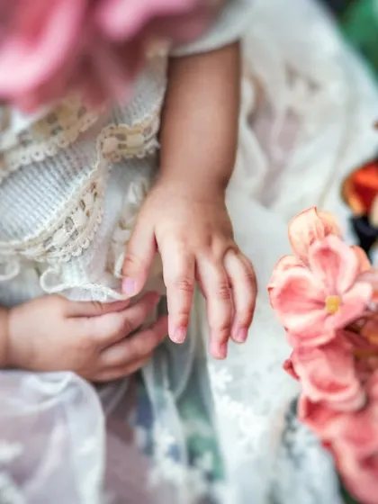 A close-up detail shot focusing on the baby's tiny hand and the delicate lace of her dress. Sometimes the smallest details tell the biggest stories.