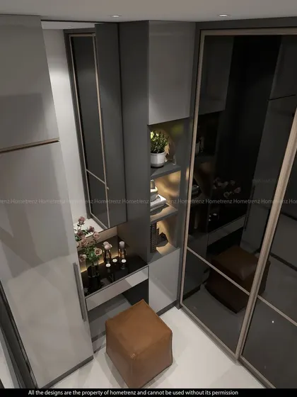A walk-in wardrobe space with a compact vanity table. The smoked glass doors and internal lighting create a high-end, boutique feel.