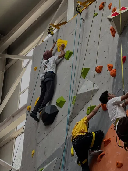 The wall is alive with action during the Warrior of the Wall competition. Multiple climbers race up the auto-belay routes simultaneously, creating an exciting and dynamic atmosphere.