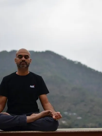 A student practices meditation against the backdrop of the mountains. This posture, Padmasana or the lotus pose, is an ideal asana for prolonged periods of meditation and pranayama.