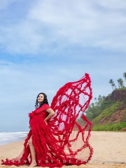 The flowing red fabric creates a sense of movement and drama in this beautiful shot, with the Varkala cliffs in the background.