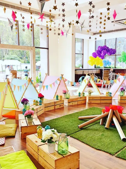 An indoor "glamping" party with individual tents, a faux bonfire, and star decorations hanging from the ceiling for a night of adventure under the stars.