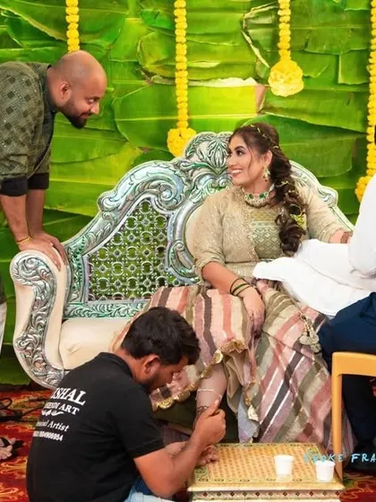 A candid moment from a mehandi ceremony, with the bride and groom admiring the artwork.