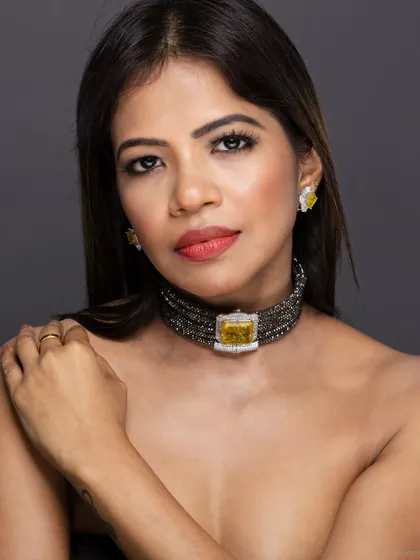 A bare-shouldered beauty shot, focusing entirely on the model's face and the statement choker.