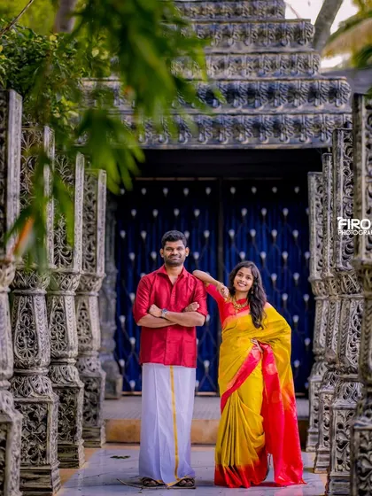 A stylish pose in a grand corridor of pillars. The couple's coordinated red and yellow outfits look striking against the intricate background.