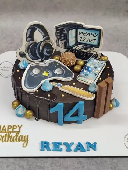 A cake for a gaming freak. This chocolate cake is topped with an edible game controller, headphones, computer, and smartphone.