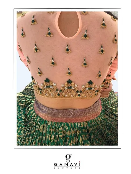 The back of a sheer net blouse, delicately embroidered with small, scattered motifs. This design showcases precision and perfection, with each bead and thread placed to create a light yet impactful pattern.