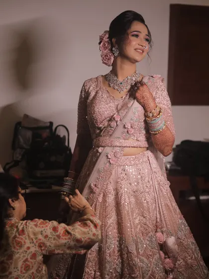 A beautiful shot of the bride getting ready, dressed in a stunning pastel pink floral lehenga.