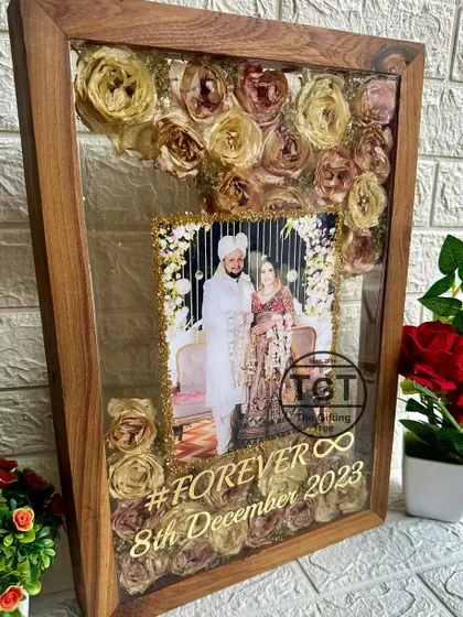 This large 13x19 inch teakwood frame has a beautiful design where the preserved varmala flowers seem to flow around the couple's photo.