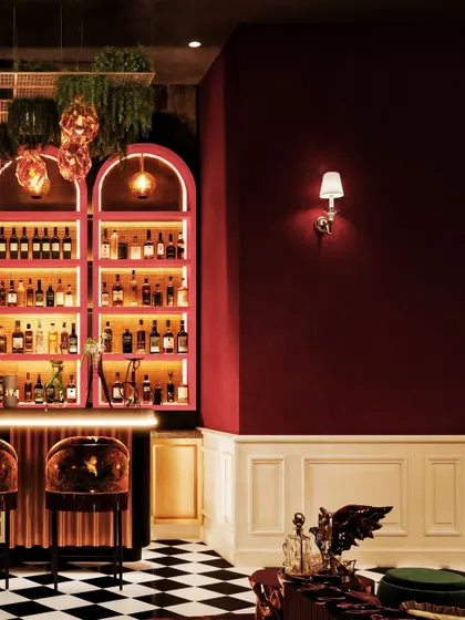 A close-up of a bar in Pune, with its pink-hued, backlit arched shelves and dramatic checkerboard floor.
