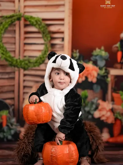 A cute little panda playing with pumpkins in a rustic, autumnal setting.