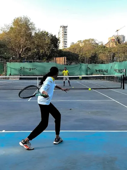 A female player executes a sharp backhand during a doubles drill, highlighting the focus on all-around skill development.