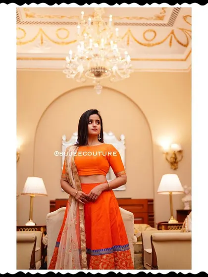 A stunning portrait of Chaitra Vasudevan wearing my custom orange lehenga creation. The outfit's vibrant color and classic design make it a standout piece for any special event.