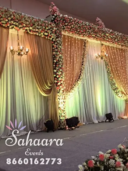 For a truly opulent look, we designed this multi-panel reception stage with rich gold and cream drapes. The intricate floral work and classic chandeliers add a touch of royal elegance to the wedding decor.