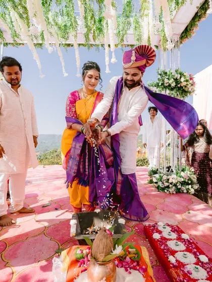 The couple performing the Laja Homa ritual together at their scenic outdoor wedding.