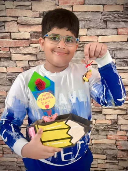 This young man is all smiles with his completed Teacher's Day gifts. He made a decorated pencil box and a cute keychain to show his appreciation.