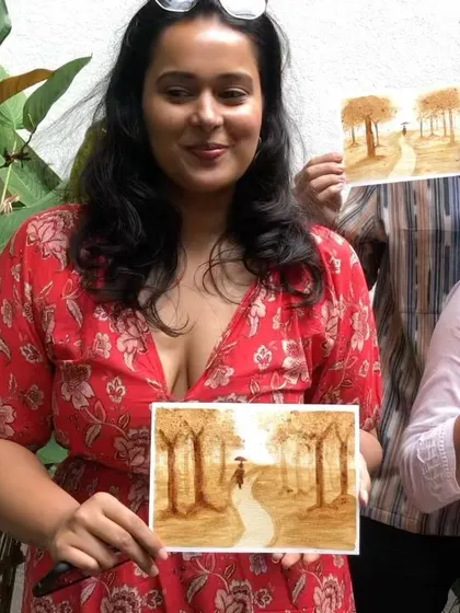 A participant proudly holding up her finished coffee painting. It's a wonderful feeling to create something beautiful with your own hands.