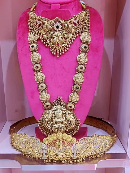 A complete bridal rental set: a grand Lakshmi haram, a matching choker, and an ornate vaddanam.