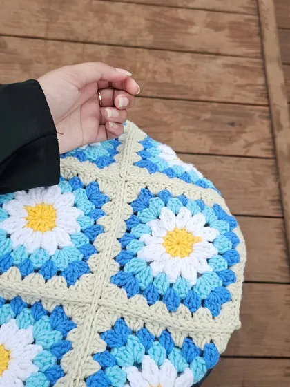 A close-up of the Daisy Tote, focusing on the texture of the daisy granny squares. I use a combination of blues, white, and yellow to create a fresh, floral pattern.