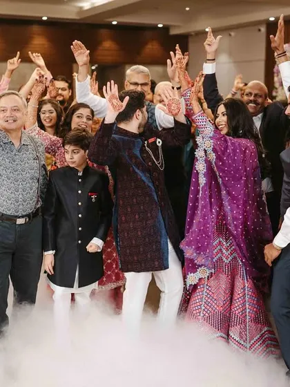 The whole family joins in for the couple's entrance, hands in the air, sharing the excitement.