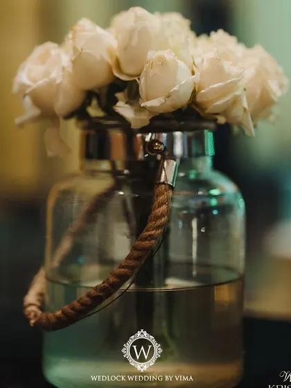 An elegant centerpiece for a Sangeet night, featuring white florals, baby's breath, and candles on a mirrored tray. The mini disco balls add a touch of sparkle and fun, tying into the party theme.