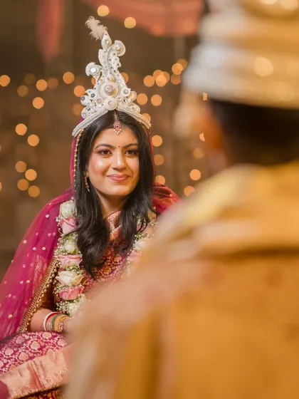 The first look between the bride and groom. The bride, wearing her traditional Bengali 'mukut', looks at her groom with love and anticipation.