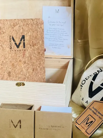 Another angle of the 'Modern Spaaces' welcome hamper, showing the branded items like the notebook, glass jar, and drawstring pouch.