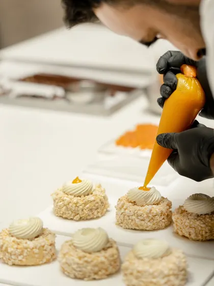 A chef piping a vibrant mango filling into a dessert. These classes are a deep dive into flavor pairings and advanced pastry components.