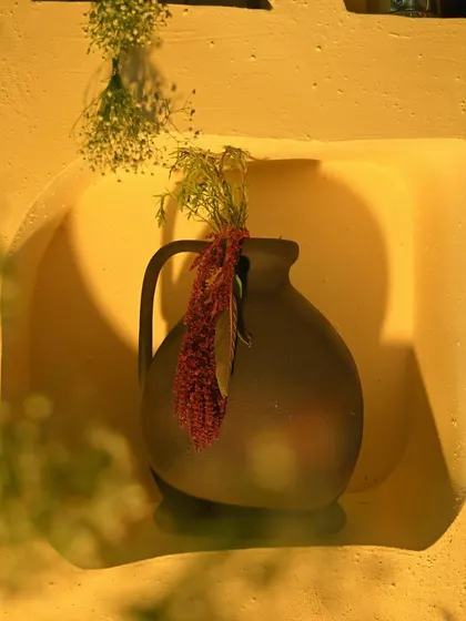 A close-up of a niche in our custom decor wall, holding an earthy terracotta vase with a simple arrangement. This highlights the rustic, handcrafted feel of the design.